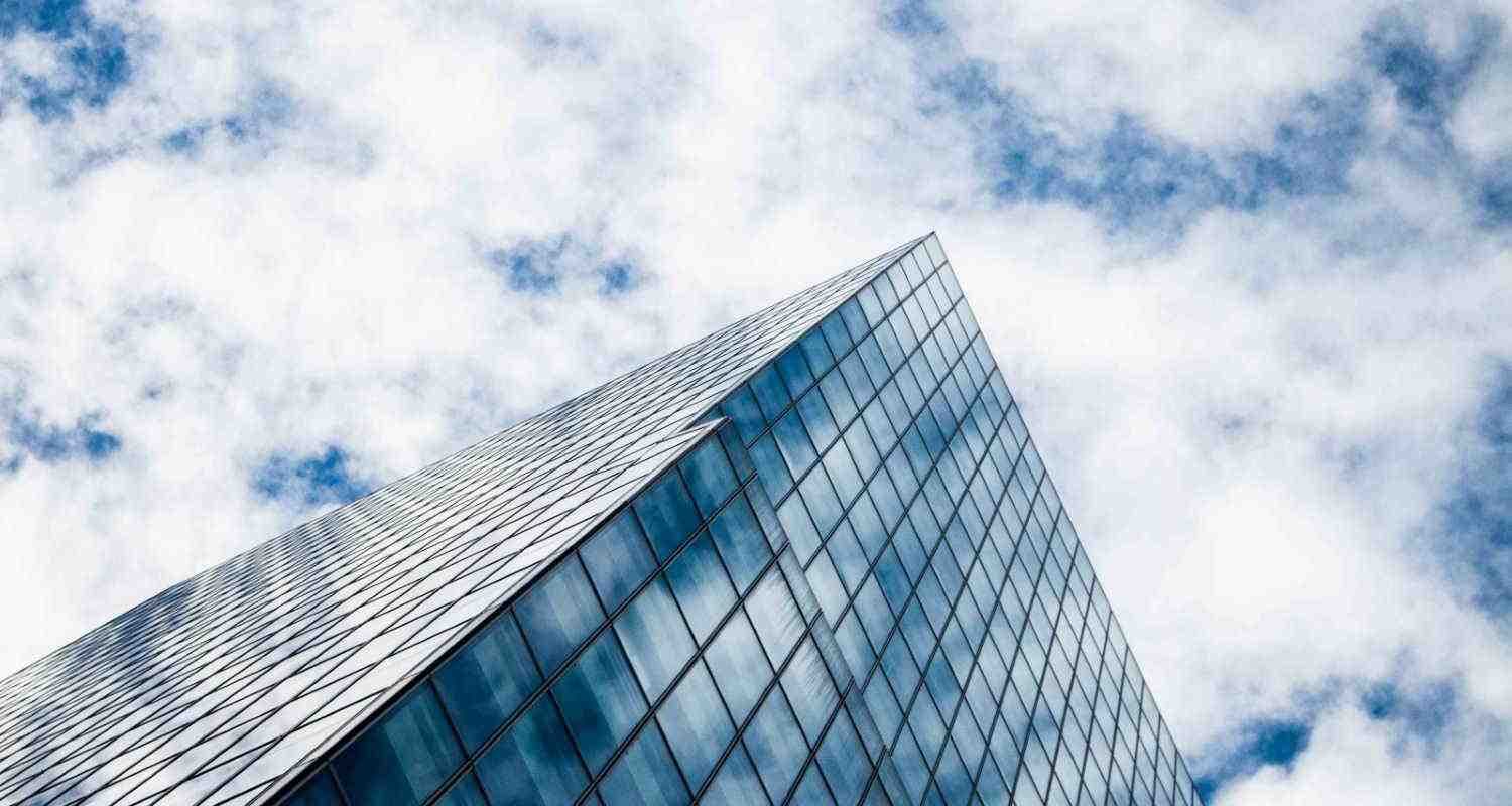 Building seen from below with blue sky and clouds.